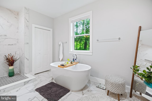 bathroom with baseboards, marble finish floor, a freestanding tub, a shower stall, and a closet