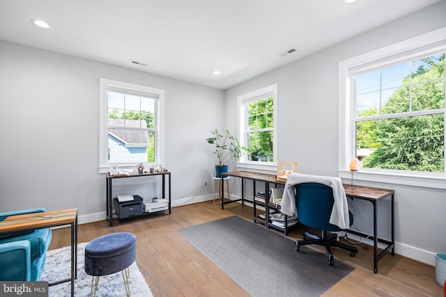 home office with wood finished floors, visible vents, and baseboards