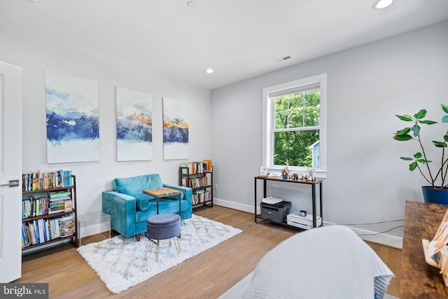 living area with recessed lighting, visible vents, baseboards, and wood finished floors