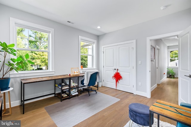 office area featuring light wood-type flooring, plenty of natural light, and attic access