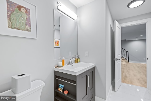 bathroom featuring toilet, tile patterned flooring, baseboards, and vanity