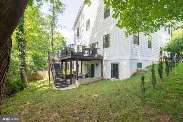 rear view of property with stairway, a deck, and a lawn