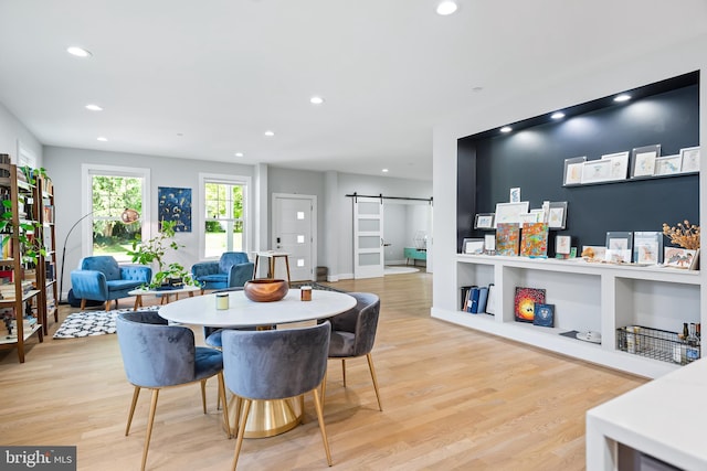 dining room with light wood-style floors, a barn door, and recessed lighting