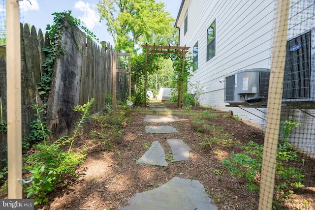 view of yard featuring a pergola, fence, and central air condition unit