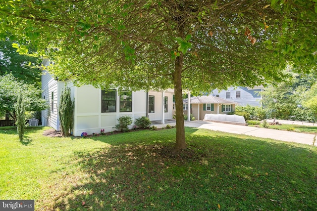 view of property hidden behind natural elements featuring driveway and a front yard