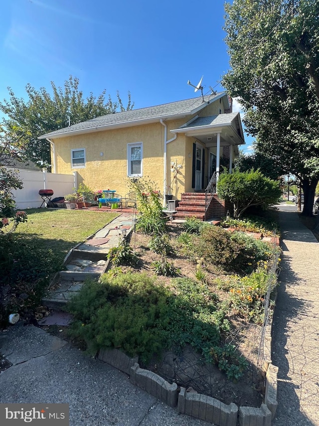 view of front of home featuring a front yard, fence, and stucco siding