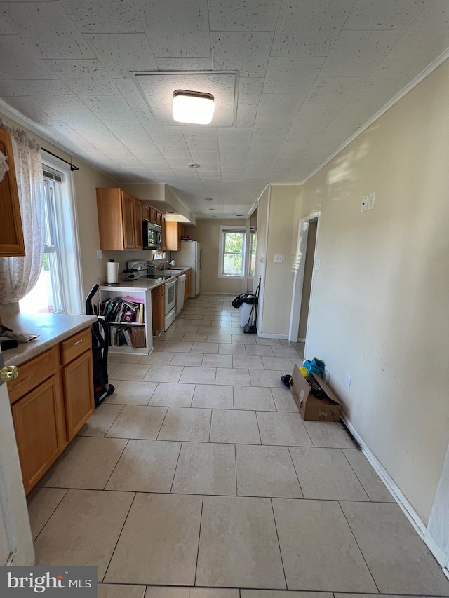 kitchen featuring light tile patterned floors, light countertops, white range with electric stovetop, brown cabinets, and stainless steel microwave