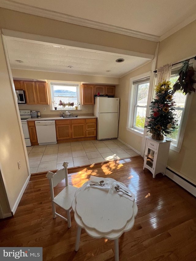 dining room with ornamental molding, light wood-type flooring, and sink