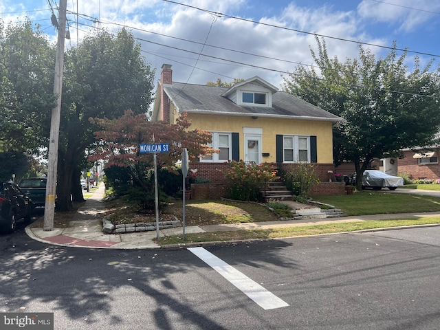 view of front of property featuring a chimney, a front lawn, and brick siding