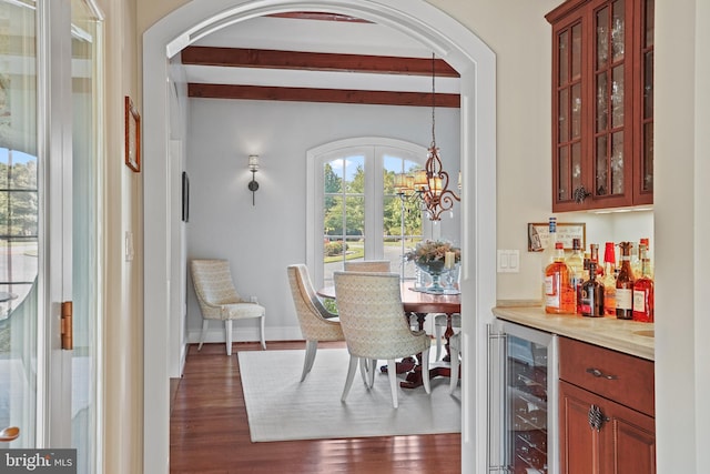 dining space featuring beamed ceiling, bar area, wine cooler, dark hardwood / wood-style flooring, and an inviting chandelier