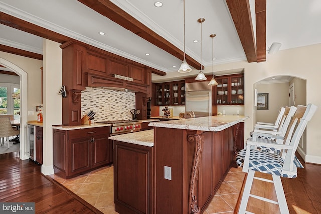 kitchen with a kitchen island, beamed ceiling, light hardwood / wood-style flooring, crown molding, and stainless steel appliances