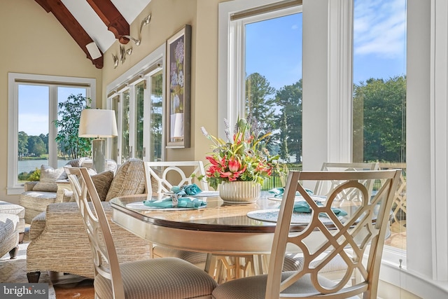 dining space featuring hardwood / wood-style flooring and vaulted ceiling with beams