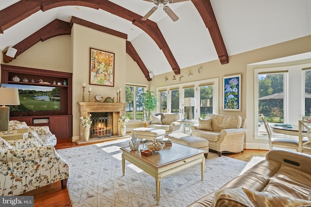 living room featuring light hardwood / wood-style flooring, ceiling fan, beam ceiling, and a healthy amount of sunlight