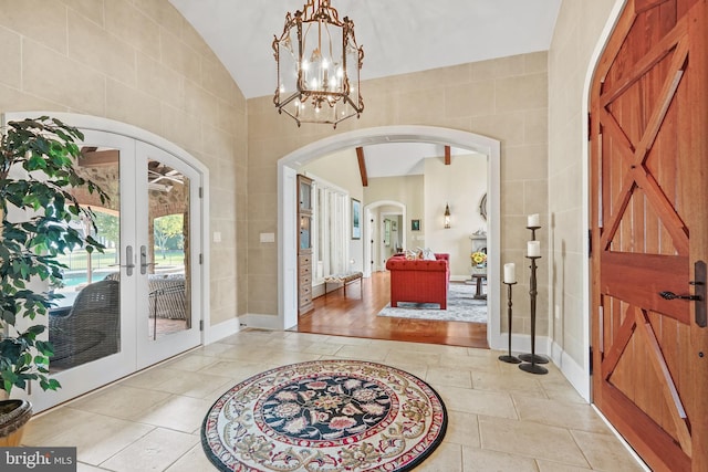 entryway with light hardwood / wood-style flooring, tile walls, lofted ceiling, and french doors