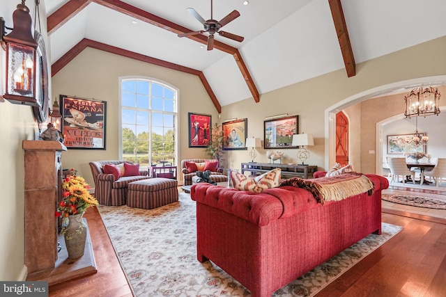 living room featuring high vaulted ceiling, ceiling fan with notable chandelier, beam ceiling, and hardwood / wood-style flooring