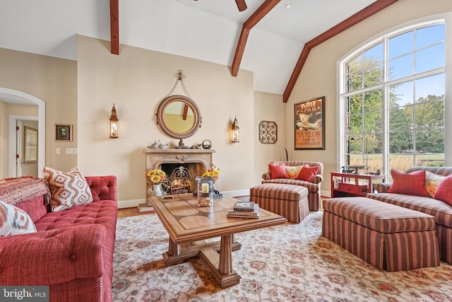 living room featuring ceiling fan, vaulted ceiling with beams, and a fireplace