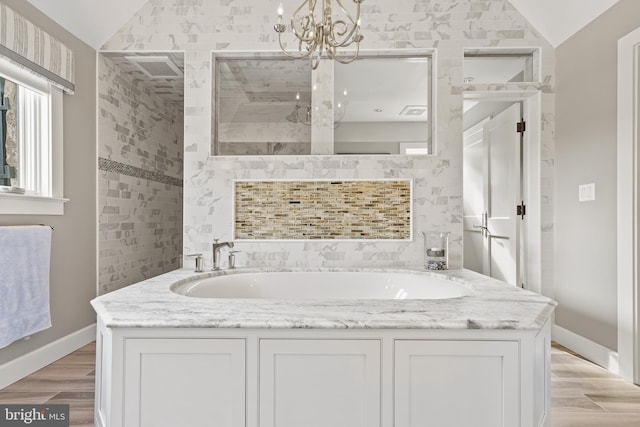 bathroom featuring shower with separate bathtub, vaulted ceiling, an inviting chandelier, vanity, and wood-type flooring