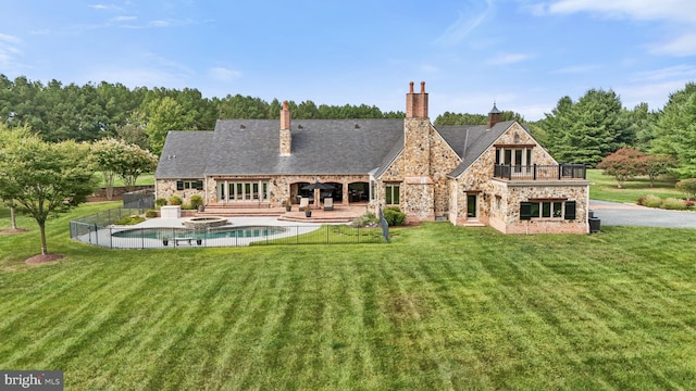 back of property featuring a balcony, a yard, and a patio area