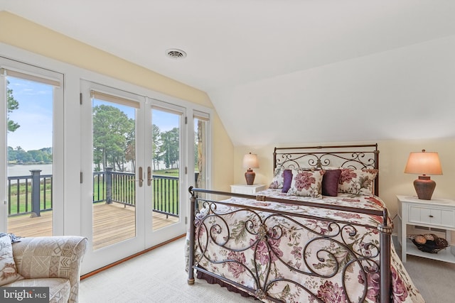 bedroom featuring vaulted ceiling, access to outside, light colored carpet, and a water view