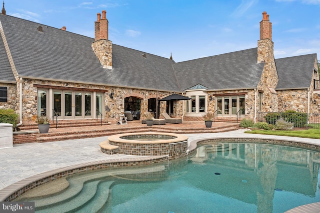 back of house with french doors, a patio area, and a pool with hot tub