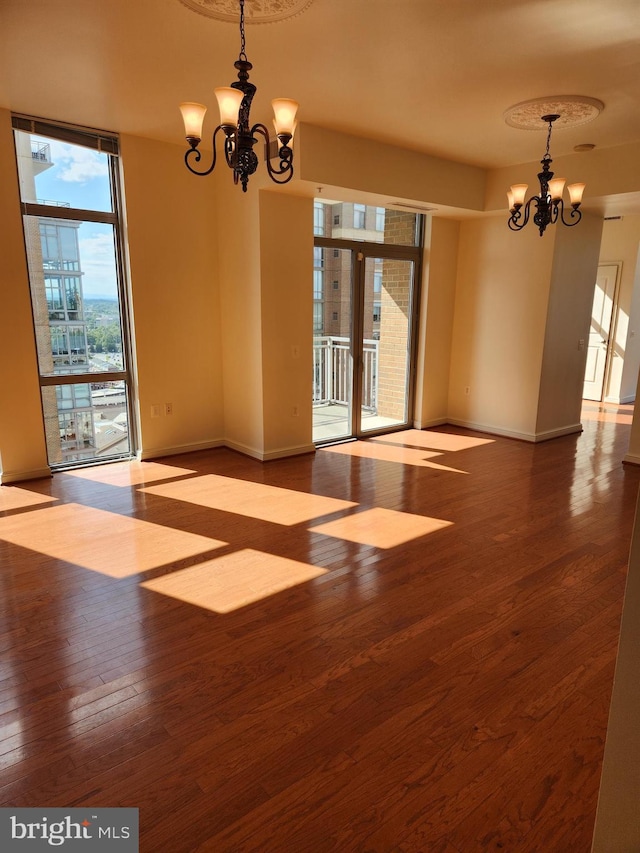 spare room featuring hardwood / wood-style floors, an inviting chandelier, and a wall of windows