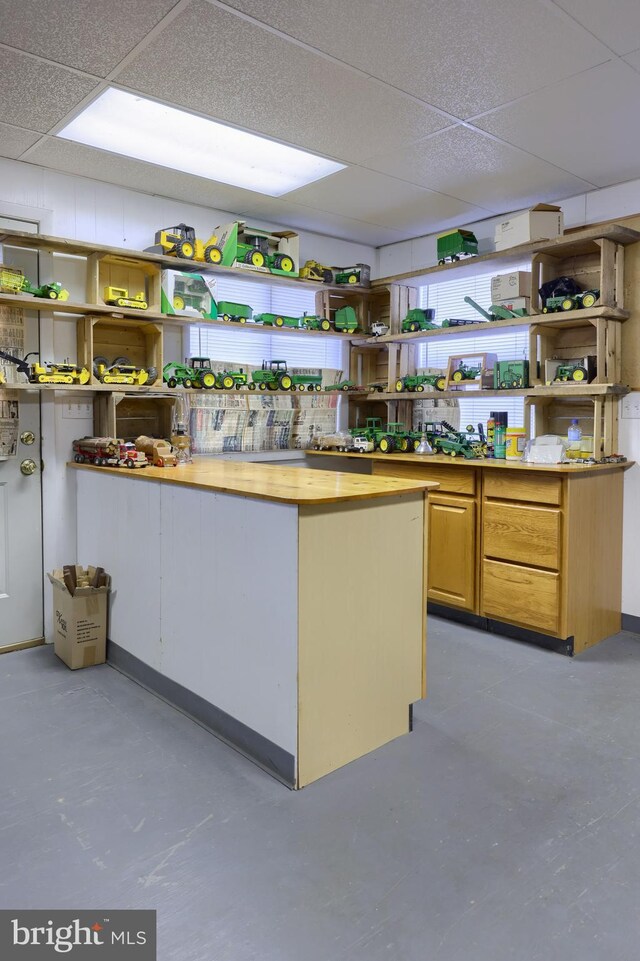 kitchen featuring concrete flooring and a drop ceiling