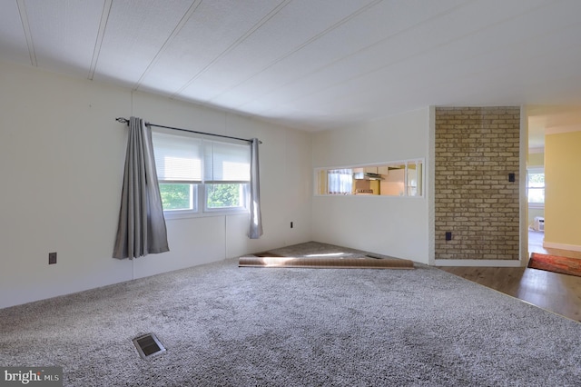 unfurnished living room with carpet and brick wall