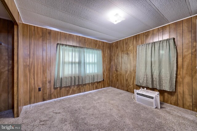 unfurnished room featuring wooden walls, carpet, and a wall mounted AC