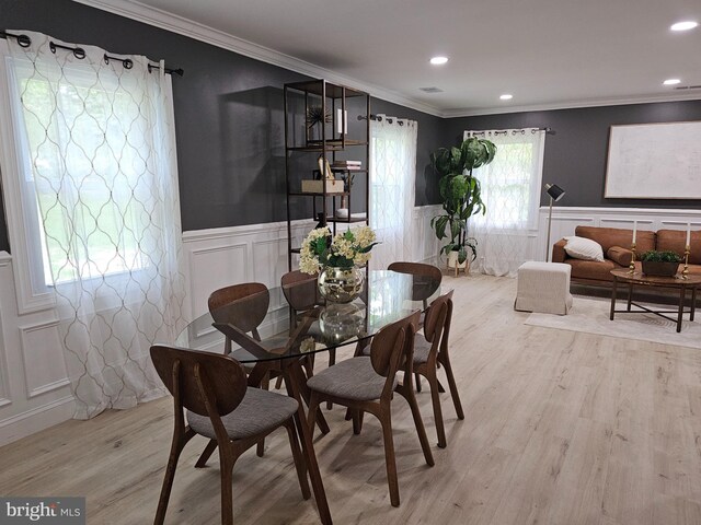 dining space featuring light wood-type flooring, ornamental molding, and a healthy amount of sunlight