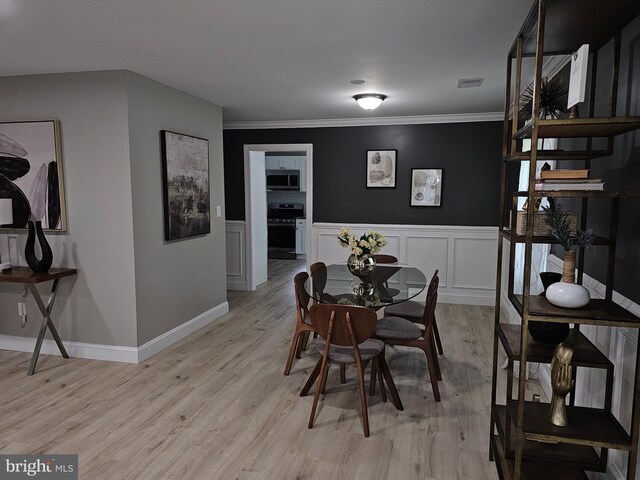 dining room with light wood-type flooring and ornamental molding