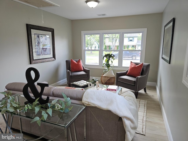 living area featuring attic access, visible vents, light wood-style flooring, and baseboards