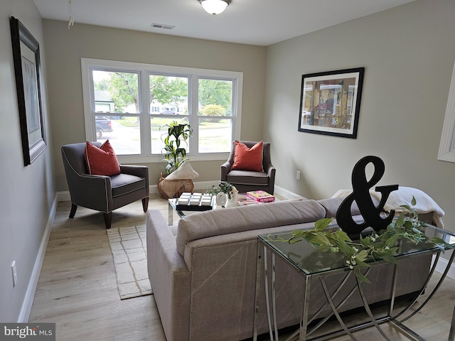 living room featuring light wood-type flooring, visible vents, and baseboards