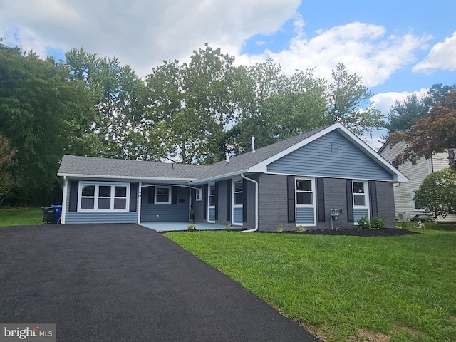 ranch-style home featuring aphalt driveway, a front lawn, and brick siding