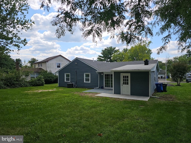 rear view of house with central AC, a patio, and a lawn