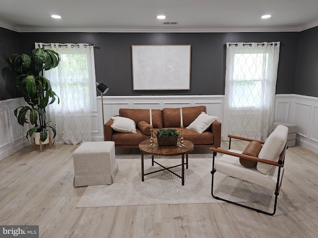 living room featuring recessed lighting, visible vents, ornamental molding, wainscoting, and light wood finished floors