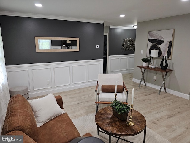 living area with light wood-style flooring, ornamental molding, a decorative wall, and recessed lighting