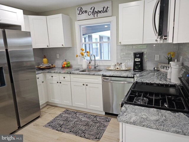 kitchen featuring light hardwood / wood-style flooring, decorative backsplash, light stone countertops, stainless steel appliances, and white cabinets