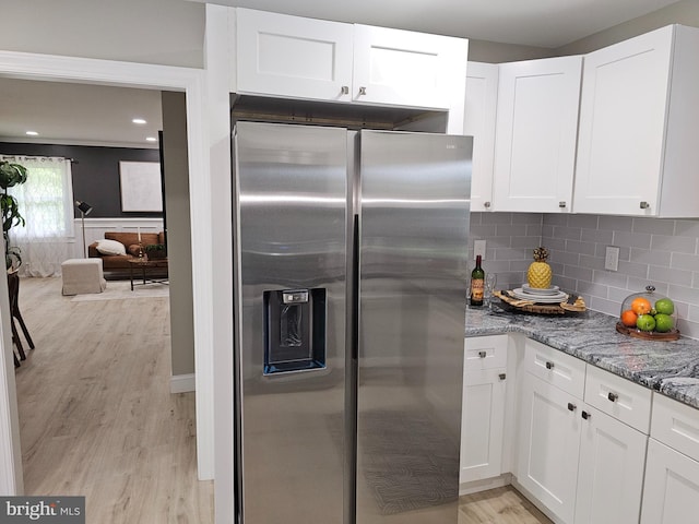 kitchen with white cabinets, decorative backsplash, light stone countertops, light wood-style floors, and stainless steel refrigerator with ice dispenser