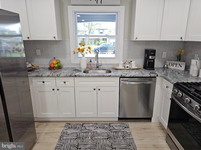 kitchen featuring light wood-type flooring, appliances with stainless steel finishes, sink, and tasteful backsplash