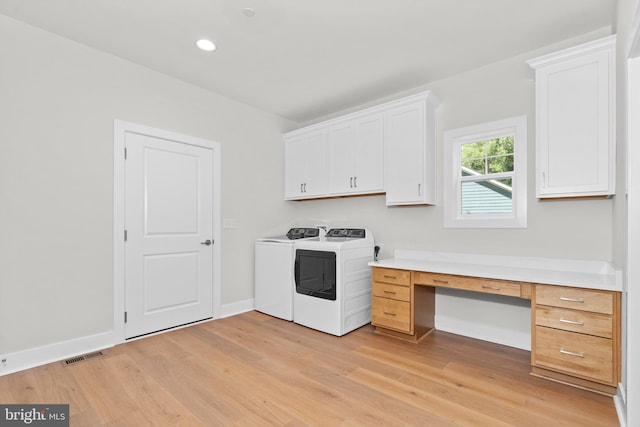 laundry area featuring light wood-type flooring, cabinets, and separate washer and dryer