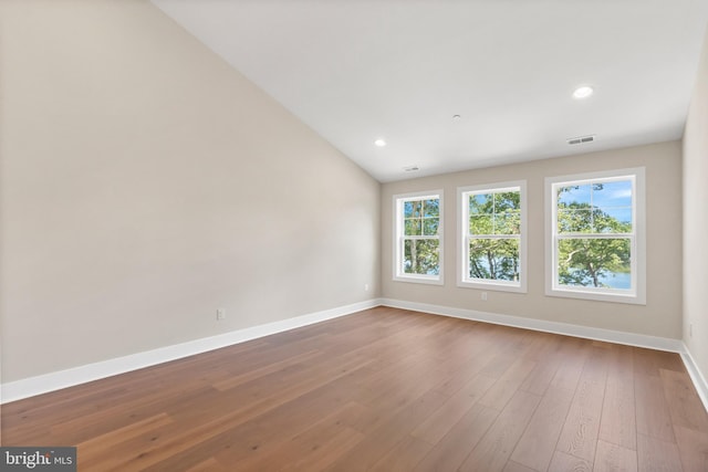 spare room with vaulted ceiling and hardwood / wood-style flooring