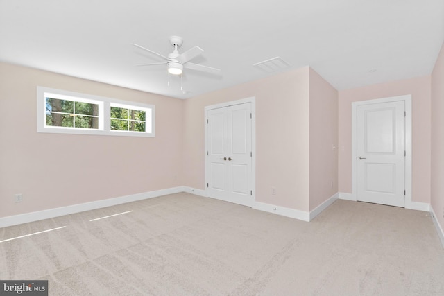 unfurnished bedroom featuring ceiling fan, light colored carpet, visible vents, baseboards, and a closet