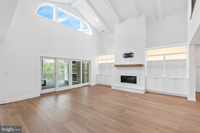 unfurnished living room with a fireplace, light hardwood / wood-style flooring, high vaulted ceiling, and beamed ceiling