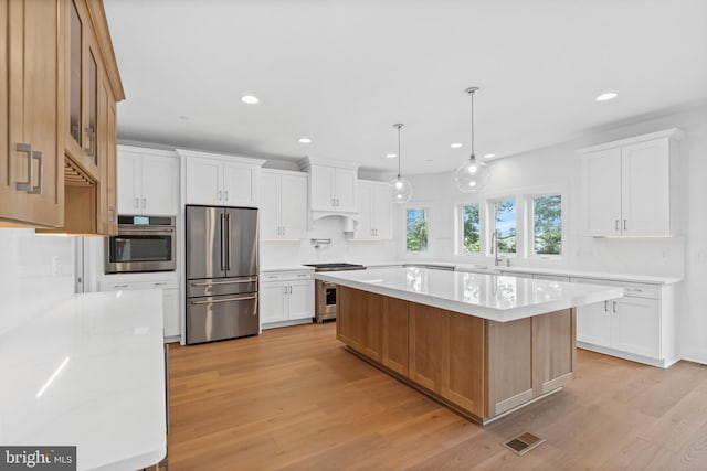 kitchen with a kitchen island, stainless steel appliances, and light wood-type flooring