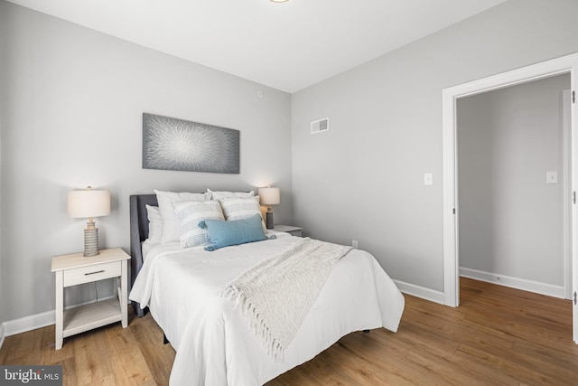 bedroom featuring visible vents, baseboards, and wood finished floors