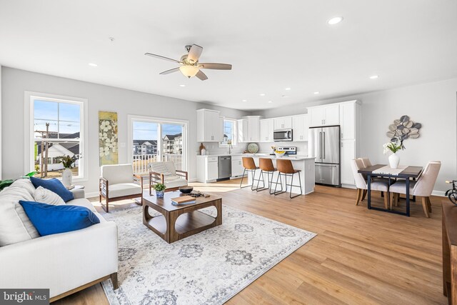 living room with light wood finished floors, recessed lighting, baseboards, and ceiling fan