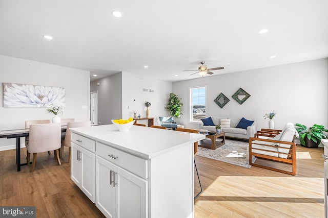 kitchen with white cabinets, recessed lighting, light wood-type flooring, and a kitchen island