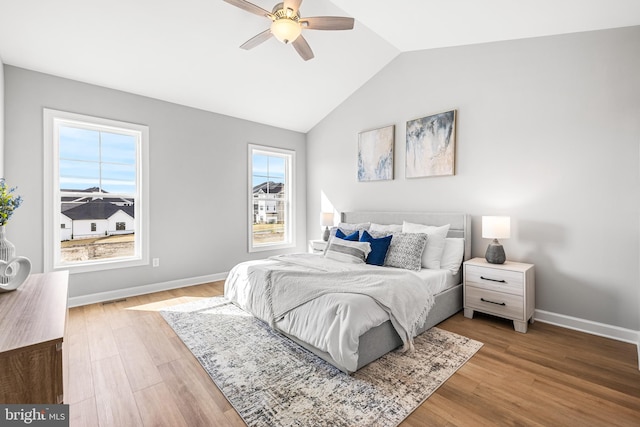 bedroom featuring visible vents, a ceiling fan, wood finished floors, baseboards, and vaulted ceiling