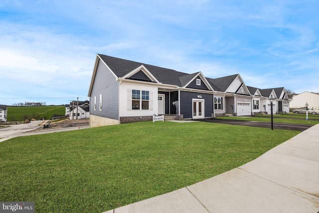 view of front facade featuring french doors, driveway, a front yard, and roof with shingles