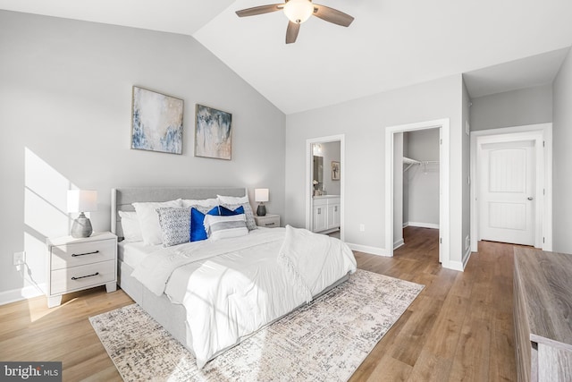 bedroom with a walk in closet, lofted ceiling, wood finished floors, and a closet